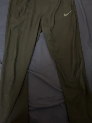 Nike Dri Fit Svarta - Säljer ett par svarta Dri Fit från Nike med klassisk logga på ena benet. Byxorna har en avslappnad passform och är perfekta för chill dagar. Materialet känns mjukt och bekvämt mot huden. Perfekta för dig som gillar sportig stil.