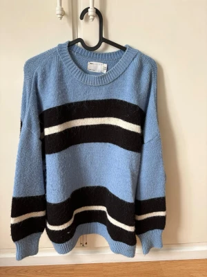 ASOS Design Striped Oversized Knit Sweater - Blue/Black/White - Size 36 - Beautiful knitted sweater from ASOS Design in a lovely light blue color with bold black and white stripes. It was bought a couple of years ago but has mostly stayed in the closet, so it’s in very good condition with plenty of life left! It has a slightly oversized, relaxed fit which makes it super cozy for autumn and winter. • Brand: ASOS Design • Size: EU 36 / UK 8 / US 4 • Condition: Very good – lightly worn and well taken care of. • Fit: Relaxed/Oversized • Material: Soft knit (doesn't itch!)