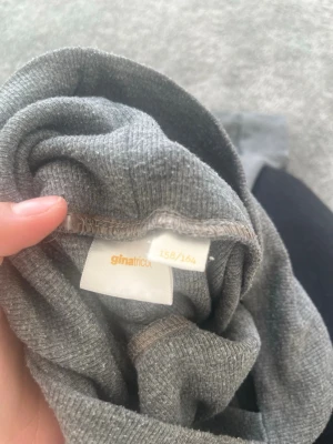 Grå leggings från Gina Tricot - Mysiga grå leggings från Gina Tricot i mjukt stretchigt material. De har en enkel, klassisk design med resår i midjan och långa ben. Perfekta att matcha med oversized tröjor eller hoodies för en chill look.