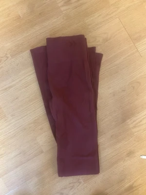 Vinröda leggings i stretchigt tyg - Snygga vinröda leggings i ett mjukt och stretchigt material. Perfekta att matcha med oversized tröjor eller hoodies. Hög midja och figurnära passform för en trendig look. Träningsbyxorna är bootcut 
