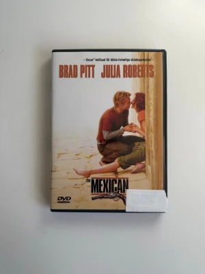DVD-film The Mexican med Brad Pitt & Julia Roberts - Succéfilmen ”The Mexican” på DVD, med Brad Pitt och Julia Roberts i huvudrollerna. Filmen är en actionkomedi som utspelar sig i Mexiko. Innehåller bonusmaterial som "Making of", bortklippta scener och trailers. Fint skick!