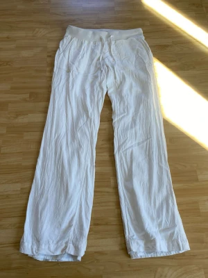 Linnebyxa - Snygga och luftiga vita linnebyxor med bred resår i midjan och raka, vida ben. Byxorna har fickor fram och är perfekta för en avslappnad och trendig stil. Materialet är linne vilket gör dem svala och bekväma. Finns även innertyg, vilket gör att den inte alls är genomskinlig 