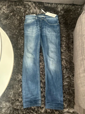 Dondup W30 - Snygga blå slim fit jeans med tvättad effekt och klassiska fem fickor. Jeansen har kontrastsömmar och bälteshällor. Perfekta för en avslappnad och trendig stil. Materialet är troligtvis bomull med stretch för extra komfort.