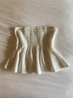 Smockad tubtopp  - Supersöt vit smockad tubtopp med volang nertill. Använd fåtal gånger, liten i storlek passar även s