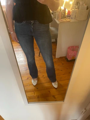 Blå flared jeans med hög midja - Säljer ett par klassiska blå jeans med flared passform och hög midja. Jeansen har fem fickor och stängs med knapp och dragkedja. Perfekta till vardagslooken och passar till det mesta! Storlek S/32