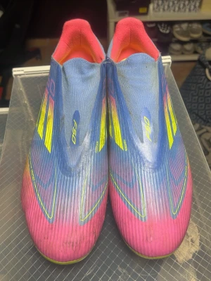 Adidas X Speedflow F50 fotbollsskor - Säljer ett par Adidas X Speedflow F50 fotbollsskor med en grym färgkombination av blått, rosa och neon-gult. Skorna har en strömlinjeformad design utan snörning och är tillverkade i syntetmaterial för maximal lätthet och snabbhet på planen. Pris kan diskuteras.