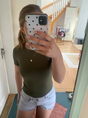 Olivgrön kortärmad body  - Snygg olivgrön body från New Yorker med korta ärmar och rund halsringning. Tight passform och mjukt stretchigt material som sitter bekvämt. Storlek XSS, men är väldigt stretchig och känns som en Xs/S!💞endast använd en gång, se bild 5 för defekt 
