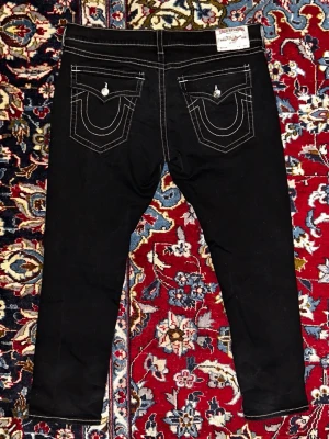 True Religion jeans - Svarta true religion jeans. Tråd lös i vänsterfickan, annars i riktigt bra skick. Bredd: 55cm. Längd: 110cm. Bara att skriva om du vill ha fler bilder eller mått.