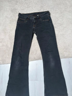 Svarta bootcut jeans från Divided - Snygga svarta bootcut jeans från Divided med orangea sömmar. Superfina bootcut med låg midja. Små i storleken så de passar som en 38 mer än 40💕 nypris 250kr💗💗😊