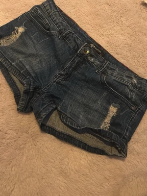 Mini jeansshorts - Säljer ett par mörkblå mini jeansshorts med slitna detaljer. 