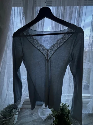 Ljusgrå långärmad topp med spets - Supersnygg ljusgrå långärmad topp från intimissmi med v-ringning och spets detaljer. Säljer pga kommer inte till användo längre. Tröjan är fotfarande i bra skick och materialet är bekvämt.