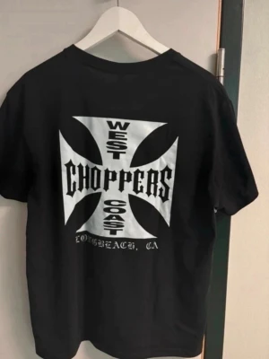 West Coast Choppers svart t-shirt - Svart t-shirt från West Coast Choppers med stort vitt tryck på ryggen och mindre logga på bröstet. Klassisk rund hals och rak passform. Perfekt för dig som gillar streetwear och tydliga tryck. 2xl men passar xl 