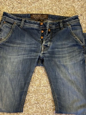 Blå jeans från Jacob Cohen - Snygga blå jeans från Jacob Cohen med klassisk femficksmodell och diskreta slitningar. Jeansen har raka ben, dubbla knappar i midjan och kontrastsömmar. Tillverkade i mjukt denimtyg för en bekväm känsla. Perfekta för en avslappnad och trendig stil. Hör av er vid frågor & funderingar, priset är inte helt hugget i sten!!