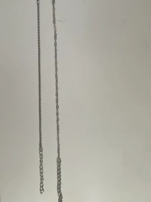 Tunt silverfärgat kedjearmband - Två  armband i silverfärgad metall. Kedjan har små, tätt sittande länkar och en enkel design som passar till många olika stilar. Perfekt för dig som gillar minimalistiska accessoarer. 45 kr för båda