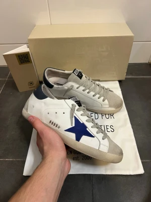 Golden Goose Superstar - Tja! Säljer nu dessa sjukt snygga Golden Goose Superstar som passar perfekt nu till sommaren! Skick 9.5/10 inga defekter alls, otroligt bra skick!! Storlek 42! BOX och DUSTBAG medföljs!! Om du har några frågor eller funderingar är det bara att höra av sig! Allt gott// MolérCloset🙌