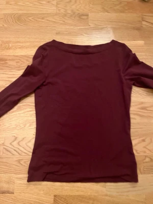 Mörkröd långärmad topp från Anna field  - En enkel och stilren mörkröd långärmad topp med rund halsring.Materialet känns mjukt och stretchigt, vilket gör den bekväm att bära hela dagen. I storleken M från Anna field.