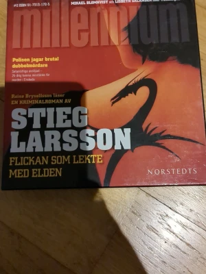 Flickan som lekte med elden CD-bok - CD-bok med kriminalromanen 'Flickan som lekte med elden' av Stieg Larsson, inläst av Reine Brynolfsson. Omslaget är rött och svart med en draktatuering och tydlig Millennium-logga. Förpackningen är fyrkantig och gjord av kartong.