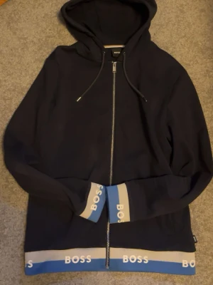 Marinblå hoodie från BOSS - Snygg marinblå hoodie från BOSS med dragkedja framtill. Från BESTSECRET. 