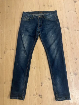 Fashion Jeans - Snygga mörkblåa jeans med slitningar i storlek 32.