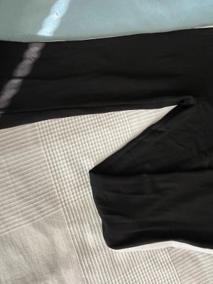 Svarta joggapants från D-XEL - Säljer ett par klassiska svarta joggapants från D-XEL i storlek 14/164. De har en hög midja och är tillverkade i ett mjukt och stretchigt material som sitter skönt på kroppen. Perfekta att matcha med oversized tröjor eller hoodies. De har en vit rand på sidan. 