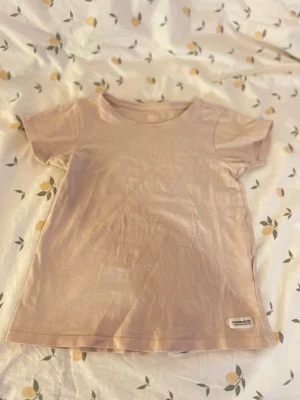Ljusrosa basic t-shirt från lager 157 barn st 140 - Enkel och stilren ljusrosa t-shirt i mjuk bomull. Klassisk rund halsringning och korta ärmar. Perfekt till vardags och lätt att matcha med olika outfits. Barn storlek 140