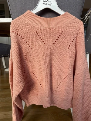 Rosa stickad tröja med hålmönster - Snygg rosa stickad tröja. Tröjan har lång ärm och avslappnad passform, perfekt för lager på lager. Köparen står för frakt.