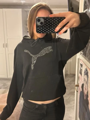 Svart hoodie från Puma - Svart hoodie från Puma med stor, mönstrad Puma-logga på bröstet. Tröjan har huva med snöre. Storlek XL men passar som S/M!! Inga större skador!!💞💞💞