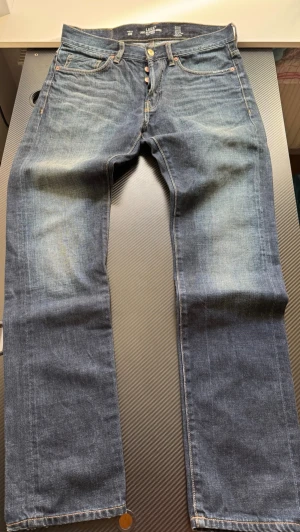 Blå raka jeans från L.O.G.G. - Snygga blå jeans från L.O.G.G. med klassisk rak passform och fem fickor. Jeansen har en lätt tvättad look och detaljer i kopparfärgade nitar. Tillverkade i slitstark denim med skinnpatch bak i midjan.