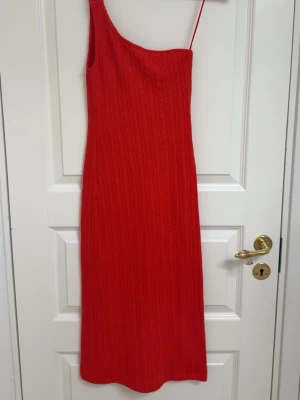 Röd one-shoulder klänning - Kommer ej till användning! En lång röd klänning med one shoulder. Den är ribbat.