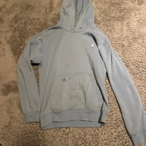 Ljusblå hoodie från Jordan - Säljer en ljusblå hoodie från Jordan med klassisk huva och känguruficka framtill. Tröjan har långa ärmar och en liten vit Jumpman-logga på bröstet. Perfekt för en avslappnad och sportig stil. Köptes för 950kr