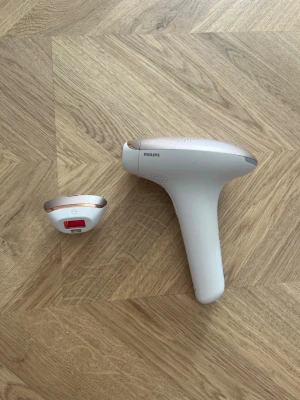 Philips IPL hårborttagning - Säljer en vit och roséguld IPL hårborttagningslaser från Philips. Har handtag och utbytbara munstycken för olika kroppsdelar. Passar för  hårborttagning hemma. Medföljer extra munstycke och kontaktuttag enligt bild.