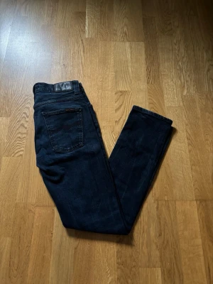 Nudie Jeans - Säljer ett par fina Nudie Jeans i modellen Tube Tom. Dom är väldigt Slim i sin modell. Inga skador finns på jeansen o dom är svarta med en nyans av mörkblå.Storlek:W30/L32 Mått 📏  Totallängd: 98,5cm Midjelängd:37cm Skriv o fråga vid funderingar! ✅