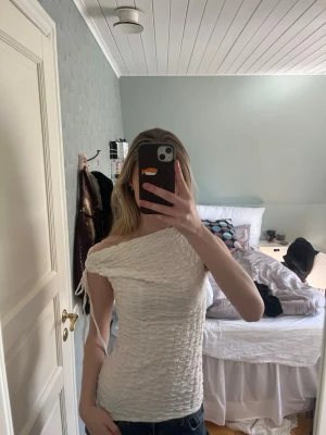 Vit offshoulder ribbad topp - Säljer en vit offshoulder topp med ribbad struktur och smickrande passform. Toppen är ärmlös och har en lätt croppad look, perfekt till jeans eller kjol. Materialet känns mjukt och stretchigt 💕💕💕💕