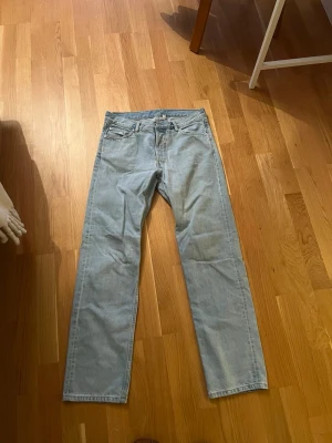 Ljusblå raka jeans från weekday - Säljer ett par klassiska ljusblå jeans från weekday med rak passform och fem fickor. Jeansen har en tidlös look och är tillverkade i slitstark denim. Perfekta för dig som gillar en clean och enkel stil.