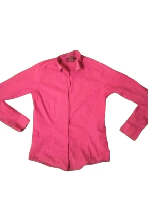 Rosa skjorta med långa ärmar - Snygg rosa skjorta med klassisk krage och långa ärmar. Skjortan har en enkel design utan synliga mönster och stängs med knappar framtill. Perfekt för dig som vill sticka ut med färg i vardagen.