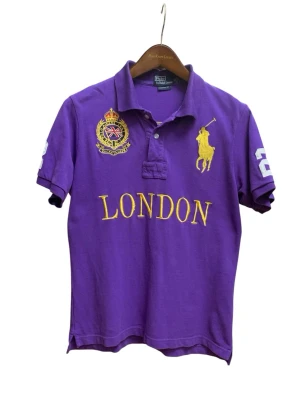Vintage Ralph Lauren piké - Vintage Authentic Polo Ralph Lauren polo shirt in purple featuring large embroidered “London” design, crest detail and number 2 on the back.  Size M Lenght 66 cm (from neck back) Wide 48 cm  Nice color, great vintage condition.   Keywords: polo ralph lauren, big pony, london polo, custom fit, designer polo, preppy, streetwear, menswear, embroidered, ralph lauren shirt
