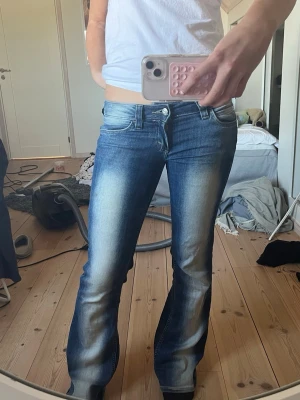 Blå bootcut jeans från Cheap Monday - Säljer ett par blå bootcut jeans från Cheap Monday med snygg slitning och ljusare partier framtill och baktill. Jeansen har klassisk femficksmodell, låg midja och en patch med logga bak i linningen. Perfekta för en avslappnad och trendig look. Obs endast lite slitna längst ner men annars är de i topp skick. 💗