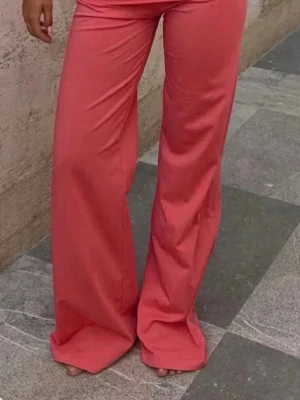 Vida rosa leggings med hög midja - Säljer ett par trendiga rosa coral pants med vida ben De har en snygg, avslappnad passform SLUTSÅLDA på Gina och prislappen är kvar helt oanvända 