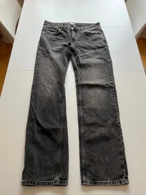 Svarta raka jeans med vintage-look - Säljer ett par svarta jeans med rak passform och lätt tvättad vintage-look. Jeansen har klassiska fem fickor och normal midja. Materialet är denim i bomull och de har en avslappnad vibe som passar till det mesta.