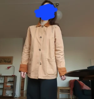 Beige rock med manchester-detaljer - Stilren beige rock med stora knappar och fyra fickor. Rak passform och mjukt tyg, perfekt för våren/sommaren! :) Passar storlek 36-40.