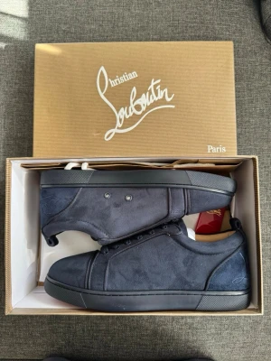 Mörkblå sneakers från L - Stilrena mörkblå sneakers från L i mocka med matchande mörkblå sula och diskreta sömmar. Klassisk låg modell med snörning och subtil logga på hälen. Perfekta för dig som gillar exklusiva och minimalistiska skor.