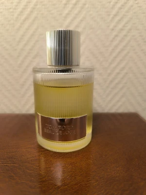 Tom Ford Beau De Jour EdP 100ml - Tom Ford Beau De Jour Eau de Parfum i en elegant, räfflad glasflaska med silverfärgat metallock och etikett. Flaskan rymmer 100 ml och har en stilren, lyxig design med guldfärgad vätska. Perfekt för dig som gillar exklusiva dofter och snygg inredningsdetalj.