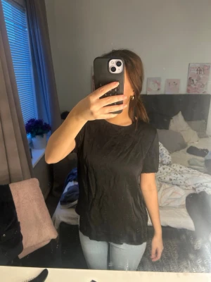 Svart basic t-shirt i bomull - En enkel svart t-shirt med rund hals och korta ärmar. Tillverkad i mjuk bomull som känns skön mot huden. Passformen är normal och t-shirten är perfekt att matcha med jeans eller kjol för en clean look.