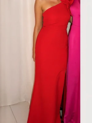 Festklänning - Snygg röd långklänning med oneshoulder-design och stor dekorativ rosett på axeln. Klänningen har en slits framtill och figurnära passform som framhäver siluetten. Perfekt för dig som vill sticka ut och känna dig extra glam. Materialet känns mjukt och bekvämt. Endast använts 1 gång och är därmed i nyskick.     Nypris 2000kr Mitt pris 1050