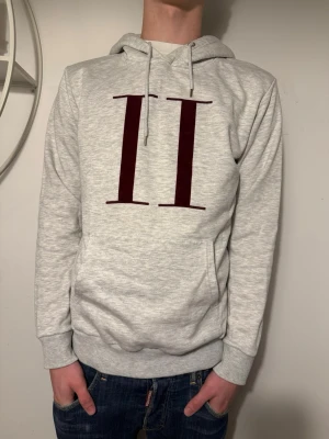 Grå hoodie från Les Deux - Snygg grå hoodie från les deux med stora sträck på bröstet. Hoodien har huva med snören och en klassisk magficka. Tillverkad i mjukt sweatshirtmaterial som är skönt mot huden. Modellen är M men sitter som S! Perfekt för en avslappnad och trendig stil. Pris kan diskuteras!💸 Strl: S Passar S/M!✅ Hör av dig om du har funderingar!👍