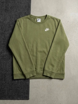 Olivgrön stickad tröja från Nike - Olivgrön stickad tröja från Nike med klassisk rund halsringning och diskret Nike-logga i vitt på bröstet. Tröjan har långa ärmar och ribbade muddar vid ärmslut och nederkant. Perfekt för en avslappnad och cool look. OBS! Liten vit fläck