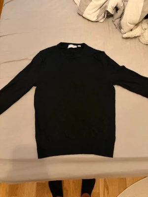 Svart tröja från Tiger of Sweden - Klassisk svart tröja från Tiger of Sweden med rund halsringning och långa ärmar. Enkel och stilren design som passar till det mesta. Tillverkad i ett mjukt material som känns skönt mot huden.