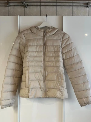 Beige vår/höst jacka - Säljer en superfin lite tynnre beige vår/höst jacka. Jackan är i gott skick förutom att änden på dragkedjan har ramlat av ( se 3 bilden) men inget som gör att den inte uppfyller sin funktion. Säljer den då den är för liten för mig som bär S, så skulle säga att den passar som en xs.