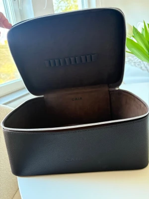 Brun necessär från CAIA - Snygg och rymlig brun necessär från CAIA Dragkedja runt och handtag på locket. Insidan har elastiska band för att hålla ordning på sminkborstar.