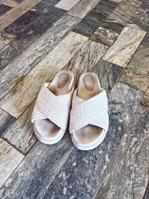 Beige flätade slip-in sandaler - Säljer ett par snygga slip-in sandaler från H&M i beige med breda, korslagda flätade band. Sandalerna har en mjuk innersula och en platåsula som ger extra höjd. Perfekta för en avslappnad och trendig look i sommar. Är i storlek 38 och använd fåtal gånger, väldigt bra skick. Köpta för 450!